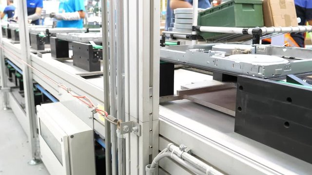 Group of workers manually assemble parts and components on a industrial assembly line