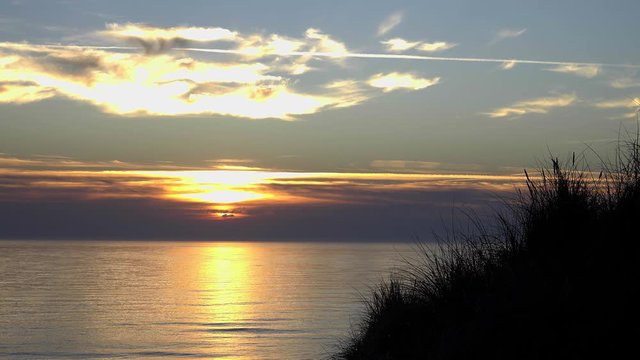 Sonnenuntergang bei stiller See auf Sylt mit D&uuml;nengras