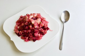 Tasty purple beet salad on the white plate.