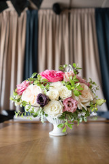 Arrangement of fresh flowers in pastel colors with a bright accent. Wedding background. table in a restaurant. different varieties of garden and shrub roses in a light vase on wooden table