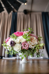 Arrangement of fresh flowers in pastel colors with a bright accent. Wedding background. table in a restaurant. different varieties of garden and shrub roses in a light vase on wooden table
