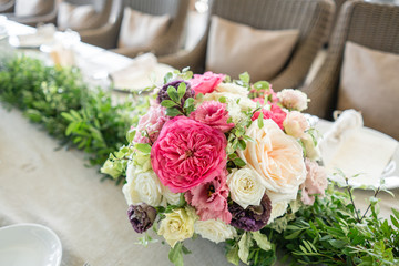 Arrangement of fresh flowers in pastel colors with a bright accent. Wedding background. table in a restaurant. different varieties of garden and shrub roses in a light vase on wooden table