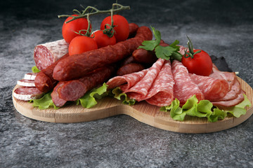 Food tray with delicious salami, pieces of sliced ham, sausage, tomatoes, salad and vegetable - Meat platter with selection - Cutting sausage and cured meat