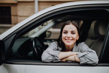 Smiling young pretty woman in the car lying on the window.