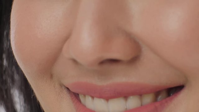Close up of a woman smiling with teeth against a white background