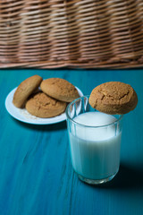 milk on a wooden background next to a plate of cookies