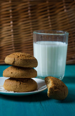 oatmeal cookies lie next to a glass of milk on a wooden background