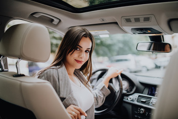 Back view of an attractive young business woman looking over her shoulder while driving a car