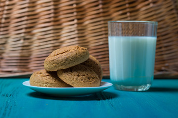 oatmeal cookies lie next to a glass of milk on a wooden background