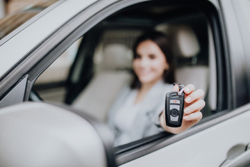 Young happy woman near the car with keys in hand. Concept of buying car. Focus on key.