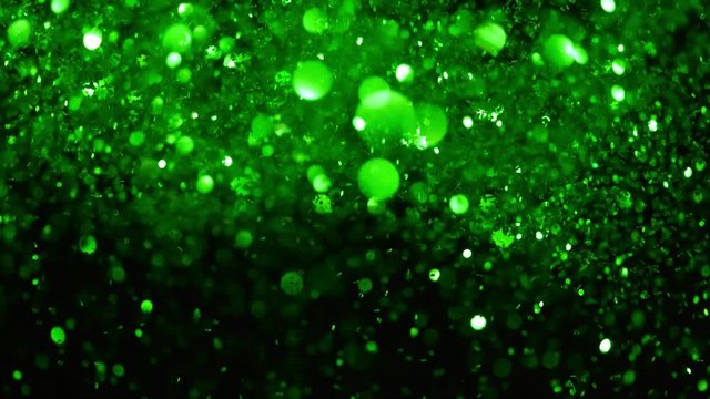 Super slow motion of glittering green particles on black background. Shallow depth of focus. Filmed on high speed cinema camera, 1000 fps.