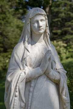 Closeup bust of woman praying statue in garden.