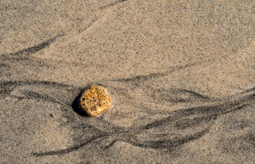 Rock and wavy lines from water flow on beach