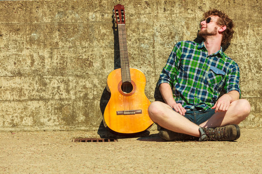 Young bearded hipster man with guitar outdoor