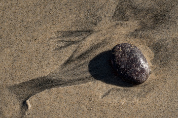 Waves around a rock on sandy ocean beach
