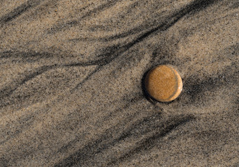 Fototapeta na wymiar Water flow lines on an ocean beach around a flat rock