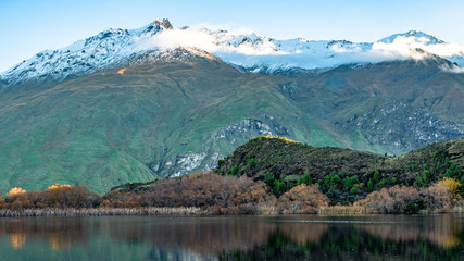 Stunning of the scenery of rocky snow mountain with the reflection of the yellow leafs tree forest in Autumn. Diamond lake track, Wanaka, New Zealand.