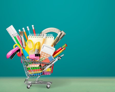 Colorful school supplies in shopping cart