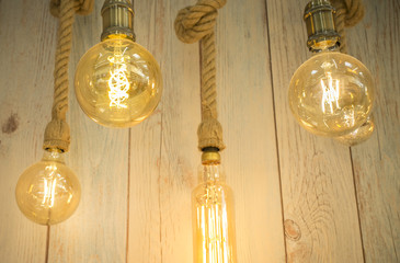 Fototapeta na wymiar Hanging light bulbs over weathered wooden background