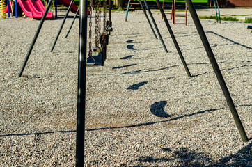 Playground rubber seat swings showing their shadows