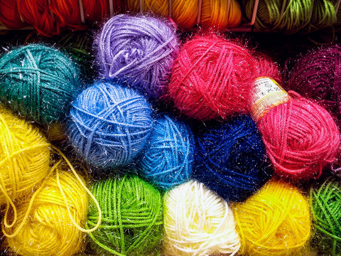 Many colorful yarn skeins on shelf in a handicraft shop