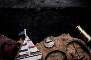 Columbus Day. Vintage worldmap and discovery equipment. Copy space on dark wood background.