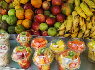 Tropical fruit sales stand. Apples, pears, bananas, tangerines and pitahayas. Fruit salad in plastic bottles with kiwi, papaya and pineapple. Delicious, nutritious and juicy.