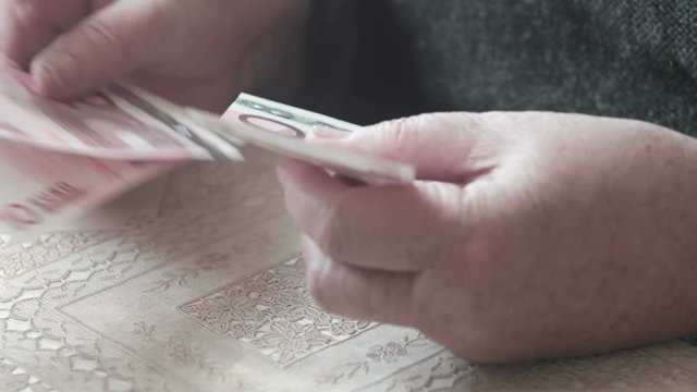 Old woman counting euro banknotes