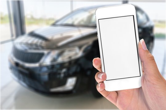 Hand holds phone and car.