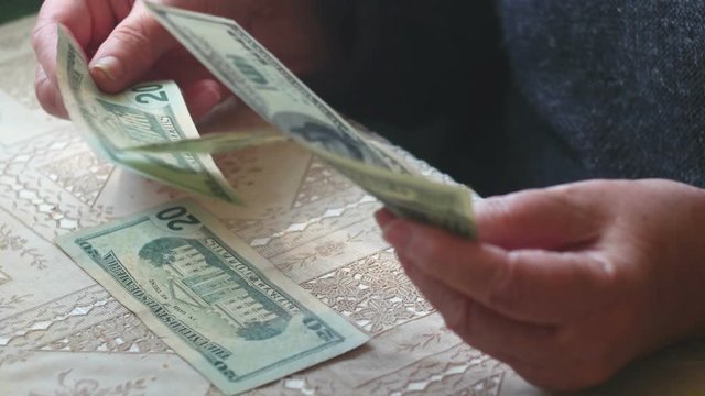 Senior woman counting dollar banknotes, closeup.