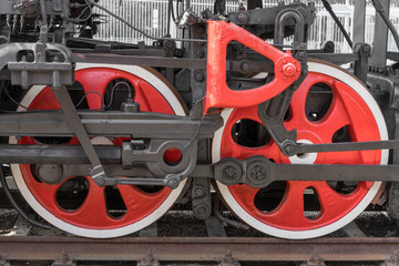 Old steam train wheels approaching, close-up. Black and red wheels. Rails and sleepers.