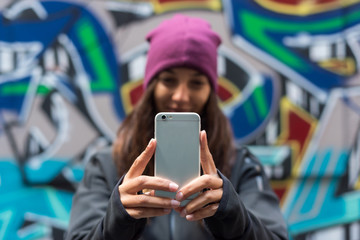 Young woman smiling and taking a selfie with her smartphone