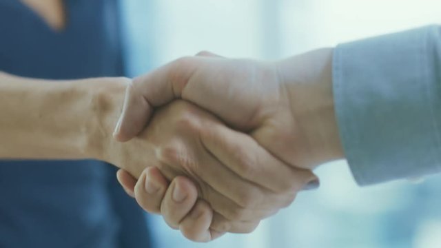 Out of Focus Businesswoman Shakes Her Hand with a Businessman. Hands in Focus. Finalizing the Deal and Concluding Contract with a Handshake.