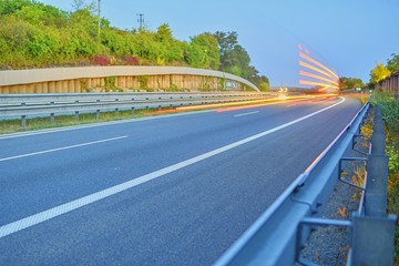 Highway at twilight with light trails. High traffic road with automobile light trails