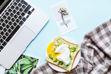Healthy Breakfast with Bread Toast and Poached Egg with Green Avocado. Flat lay desktop with laptop