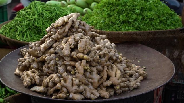 a shallow depth of filed showing a large bowl of ginger with various vegetables in the back