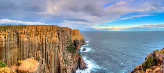 The sun hitting the top of the cliffs at Cape Raoul