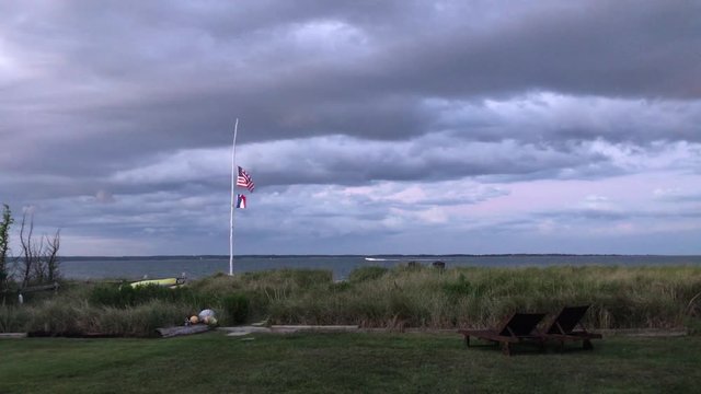 American Flag, French Flag blowing in the wind with foreboding clouds overlooking bay 