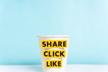 Share click like labels. Social media marketing news. Paper coffee cup on blank blue background.