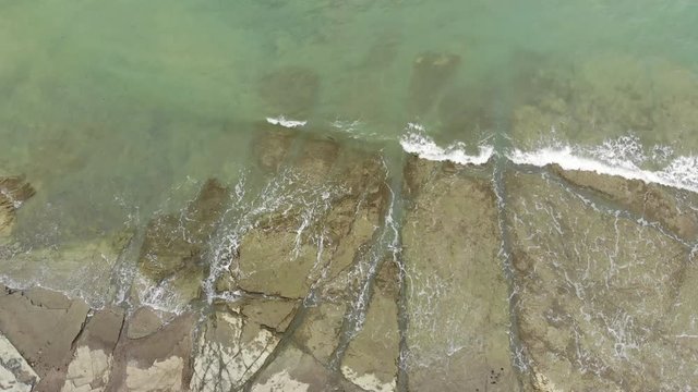 Overhead shot of waves breaking on mudstone pavement, part of the Miocene Esmeraldas Geological Formation on the Pacific coast of Ecuador.
