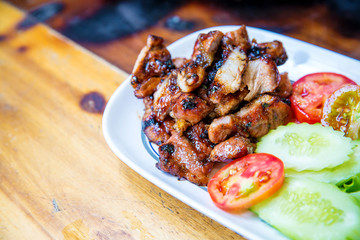 Sliced pork roasted thai style with green leaves salad on rustic plate with cutlery. charcoalboiled pork neck Grill pork Thai style food