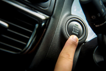 Car Push start.Closeup of hand pushing a start button of a car while steering the car.finger pressing the Engine start stop button of a car.