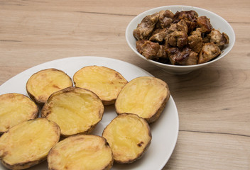 Baked potatoes on a plate and fried meat.