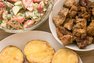 Baked potatoes on a plate and fried meat and salad.