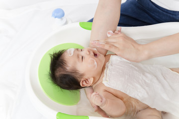 Fototapeta na wymiar 新生児の入浴・沐浴方法を説明するマニュアル用写真、洗顔の手順。