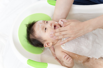 Fototapeta na wymiar 新生児の入浴・沐浴方法を説明するマニュアル用写真、洗顔の手順。