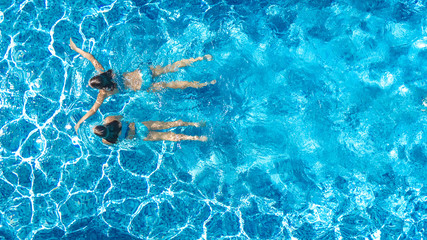 Aerial drone view of children in swimming pool from above, happy kids swim on inflatable ring...