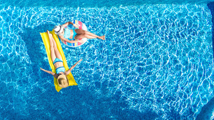 Aerial drone view of children in swimming pool from above, happy kids swim on inflatable ring...