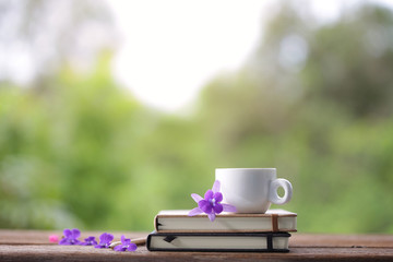 White cup and notebook with flower at outdoor