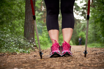 Close-up. Active mature lifestyle. Senior woman nordic walking in a countryside park.  Lifestyle concept